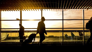 silhouettes of passengers against an airport at sunrise